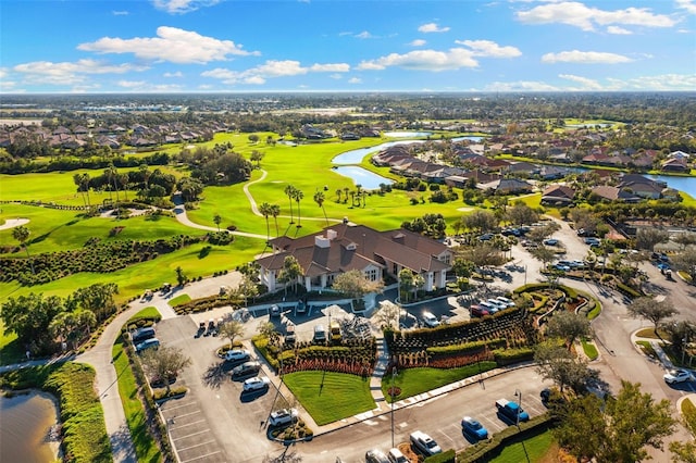 drone / aerial view featuring golf course view, a water view, and a residential view