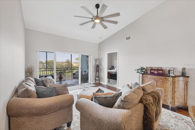 living area with visible vents, baseboards, a ceiling fan, wood finished floors, and high vaulted ceiling