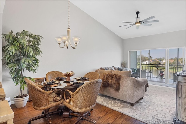 dining room with ceiling fan with notable chandelier, high vaulted ceiling, and wood finished floors