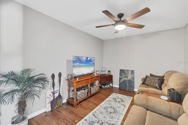 living area with a ceiling fan, baseboards, and wood finished floors