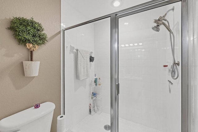 bathroom featuring toilet, a shower stall, and a textured wall