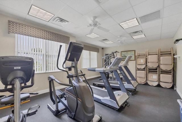 gym with a ceiling fan, a drop ceiling, visible vents, and baseboards