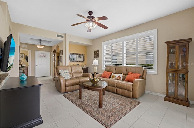 living area with arched walkways, visible vents, ceiling fan, and light tile patterned floors