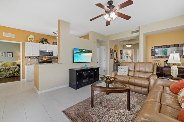 living room with light tile patterned floors, baseboards, visible vents, and a ceiling fan