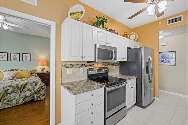 kitchen featuring tasteful backsplash, visible vents, dark stone counters, stainless steel appliances, and white cabinetry