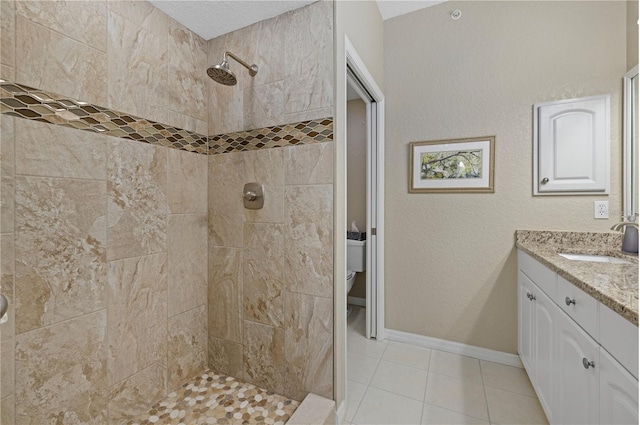 full bath featuring toilet, baseboards, a tile shower, and vanity