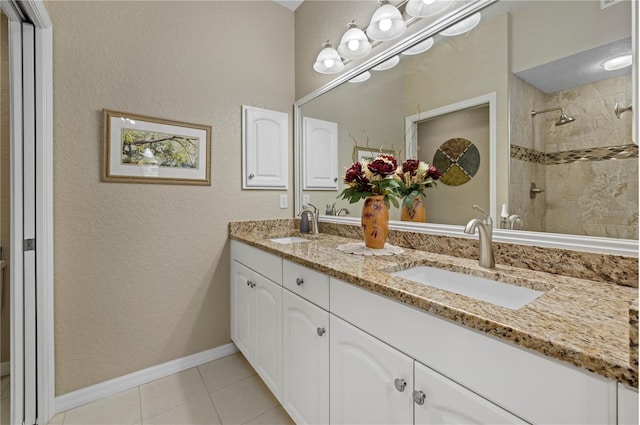 full bath with double vanity, tiled shower, a sink, and tile patterned floors