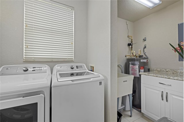 laundry room featuring washer and clothes dryer, light tile patterned floors, cabinet space, a textured wall, and electric water heater