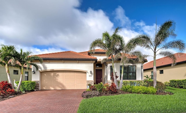 mediterranean / spanish house with a garage, stone siding, decorative driveway, and stucco siding