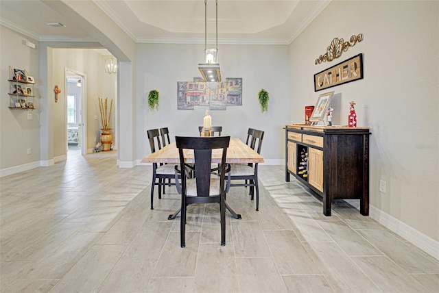 dining space featuring baseboards, arched walkways, a raised ceiling, and ornamental molding