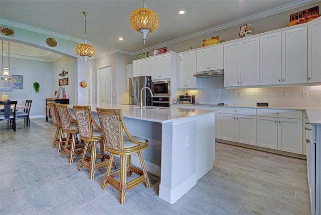 kitchen with an island with sink, white cabinetry, light countertops, and decorative light fixtures