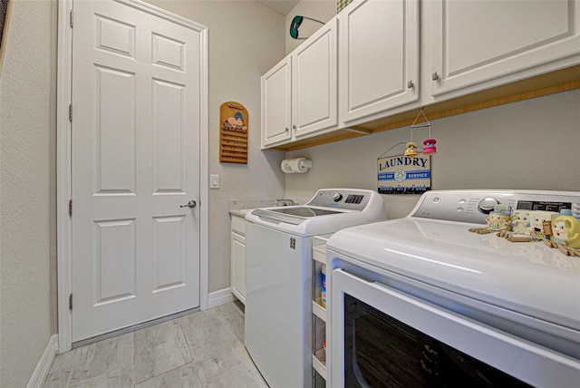 laundry area with washing machine and dryer, cabinet space, and baseboards