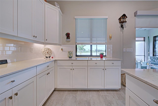 kitchen with white cabinetry, decorative backsplash, and light stone countertops