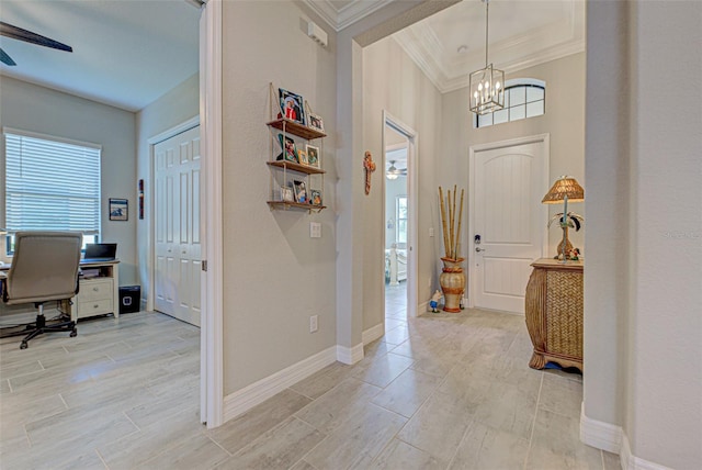 foyer with baseboards, wood finish floors, ceiling fan with notable chandelier, and crown molding