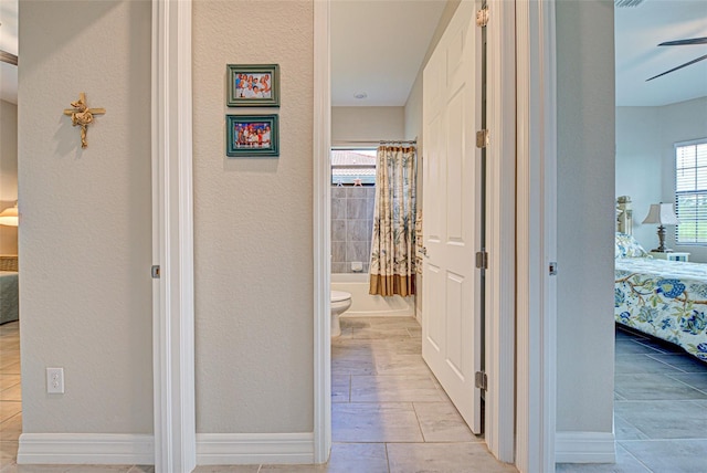 hallway with a textured wall, baseboards, and wood finish floors