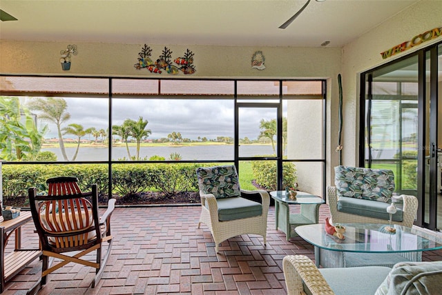 sunroom / solarium with ceiling fan and a water view