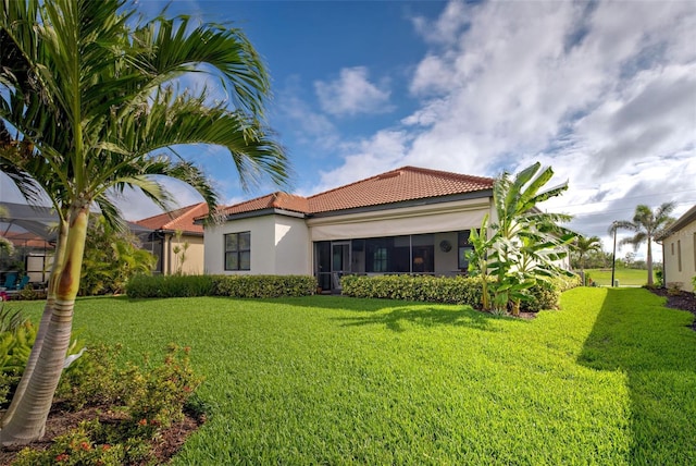 rear view of house with a yard, a tile roof, and stucco siding