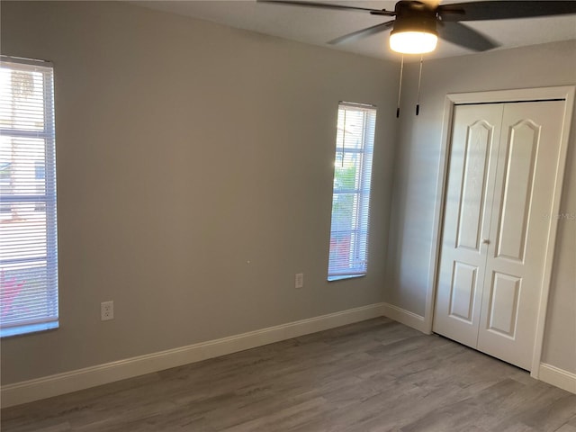 unfurnished bedroom featuring light wood finished floors, ceiling fan, baseboards, and a closet