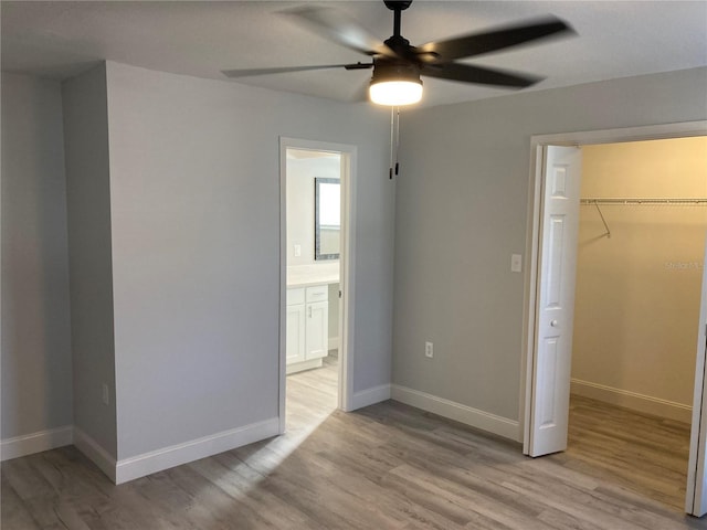 unfurnished bedroom featuring light wood finished floors, a spacious closet, baseboards, and a closet