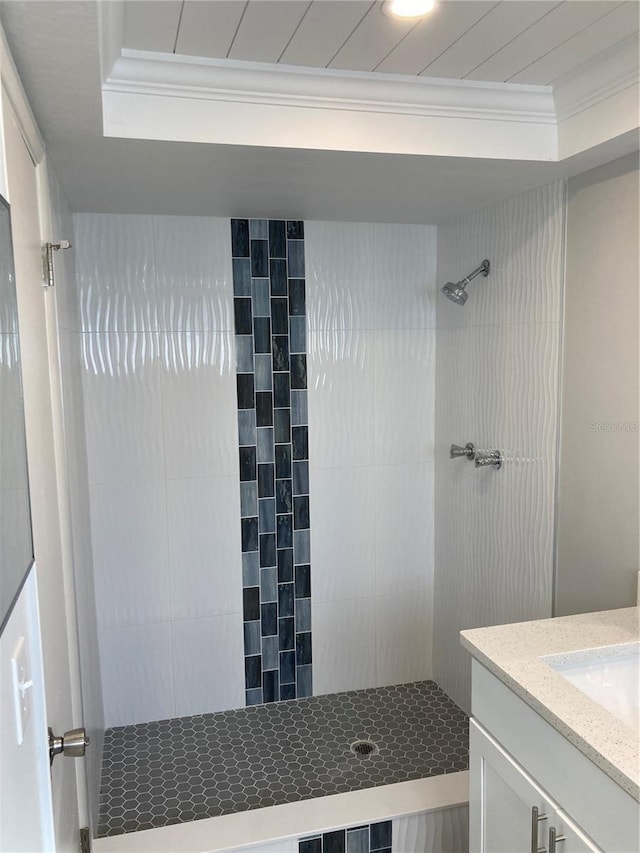 full bath featuring ornamental molding, a tile shower, and vanity