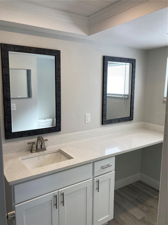 bathroom featuring toilet, ornamental molding, wood finished floors, and vanity