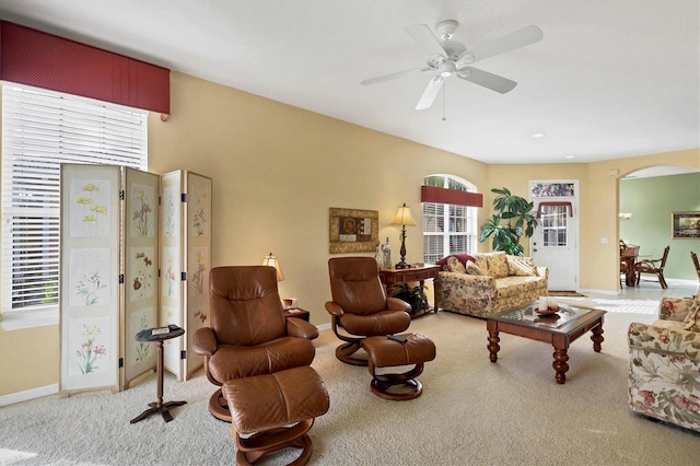 living room with light carpet, baseboards, arched walkways, and ceiling fan