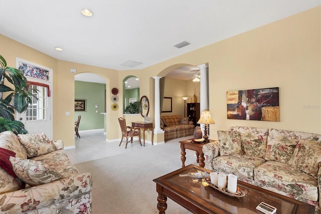 living room featuring arched walkways, decorative columns, light colored carpet, visible vents, and baseboards