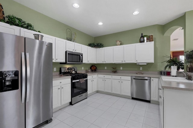 kitchen with appliances with stainless steel finishes, light countertops, white cabinetry, a sink, and recessed lighting