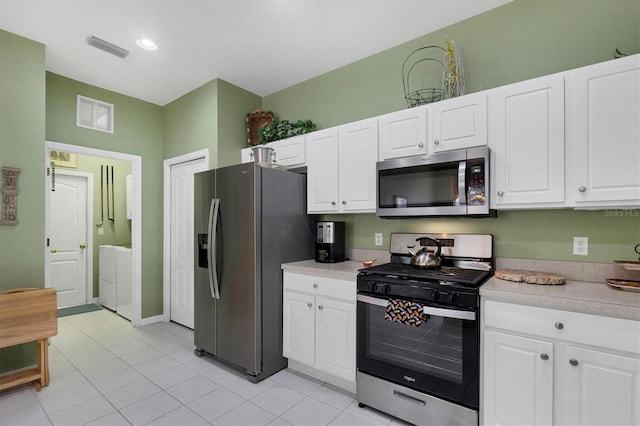 kitchen featuring visible vents, white cabinets, light countertops, appliances with stainless steel finishes, and independent washer and dryer