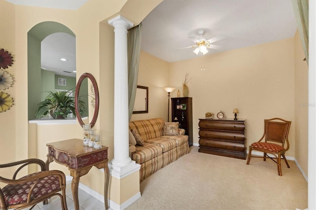 living room featuring decorative columns, baseboards, a ceiling fan, and light colored carpet