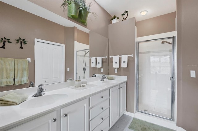 bathroom with double vanity, a shower stall, a sink, and tile patterned floors