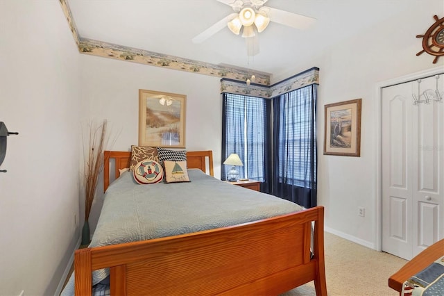 bedroom with a closet, light carpet, ceiling fan, and baseboards