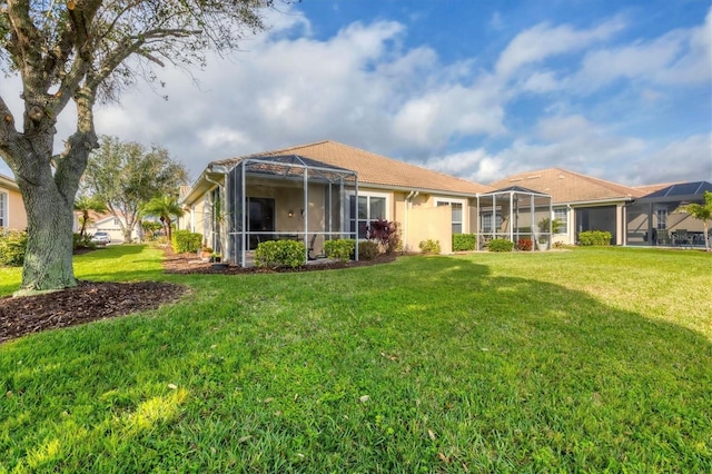 rear view of house with a yard and a lanai