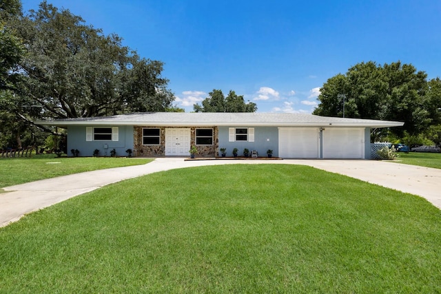 single story home with an attached garage, stone siding, concrete driveway, and a front yard