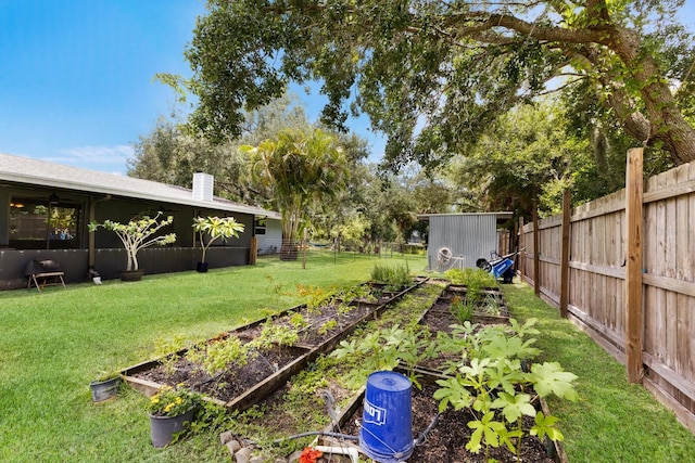 view of yard featuring an outbuilding, a storage shed, a fenced backyard, and a vegetable garden