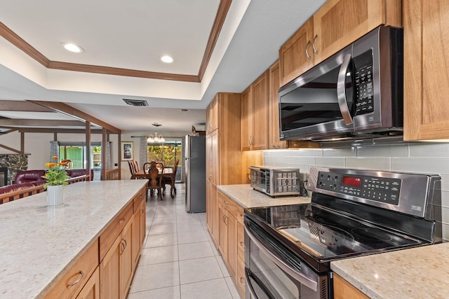 kitchen featuring stainless steel appliances, a tray ceiling, crown molding, and decorative backsplash