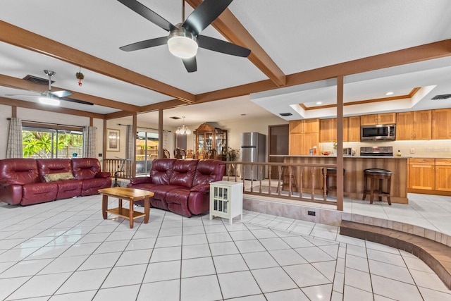 living room with ceiling fan with notable chandelier, beam ceiling, visible vents, and light tile patterned floors