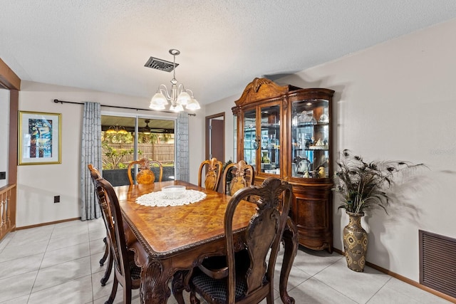 dining room with a textured ceiling, light tile patterned flooring, visible vents, and an inviting chandelier