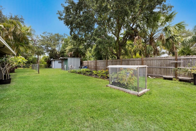 view of yard featuring an outbuilding, a storage shed, fence, and a vegetable garden