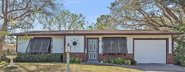 single story home featuring concrete driveway, brick siding, and a front lawn