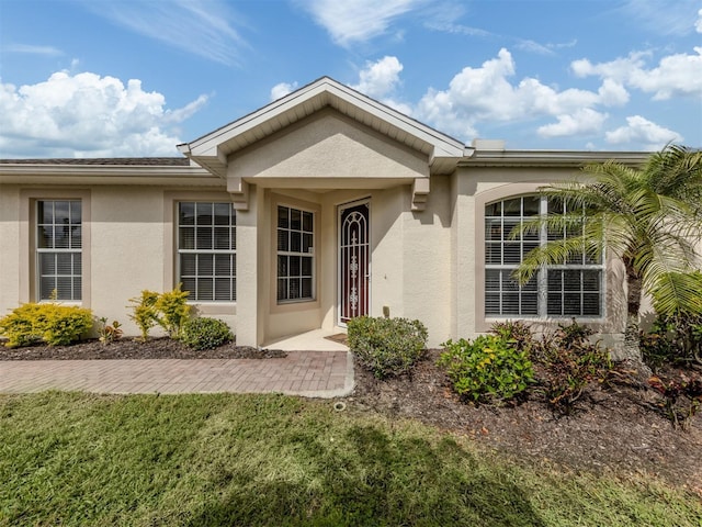 property entrance featuring a yard and stucco siding