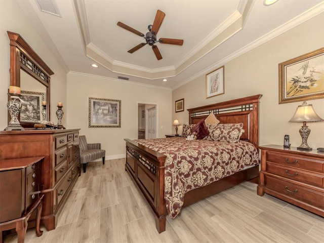 bedroom with visible vents, a tray ceiling, light wood-style flooring, and crown molding