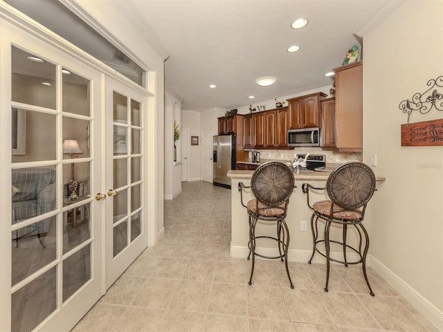 kitchen with a breakfast bar, french doors, stainless steel appliances, decorative backsplash, and a peninsula