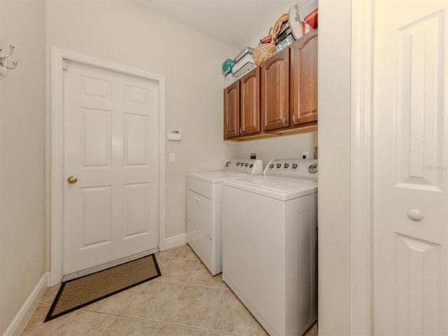 laundry area with cabinet space, light tile patterned floors, baseboards, and washing machine and clothes dryer