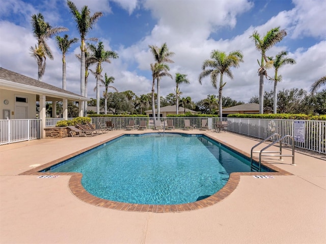 community pool with a patio area and fence