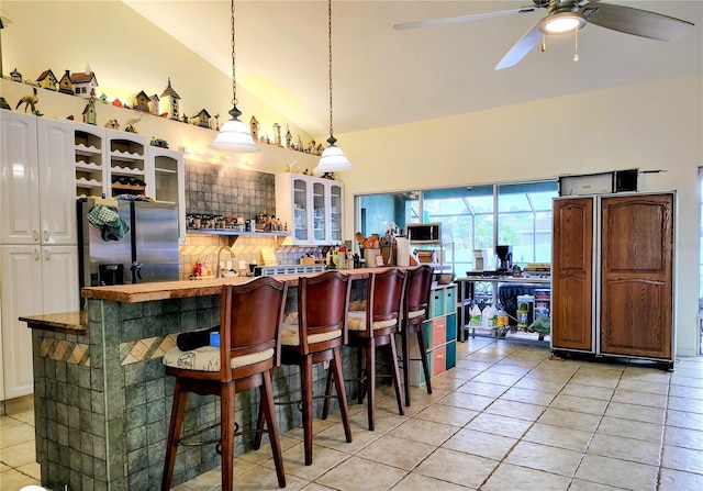 23495 Altman Ave, Punta Gorda, FL 33980 - interior space featuring a kitchen bar, light tile patterned floors, stainless steel appliances, ceiling fan, and glass insert cabinets