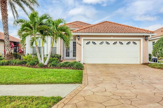 mediterranean / spanish-style house featuring a garage, driveway, a front yard, and stucco siding