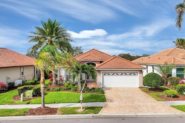 mediterranean / spanish house with driveway, a garage, a tile roof, a front lawn, and stucco siding