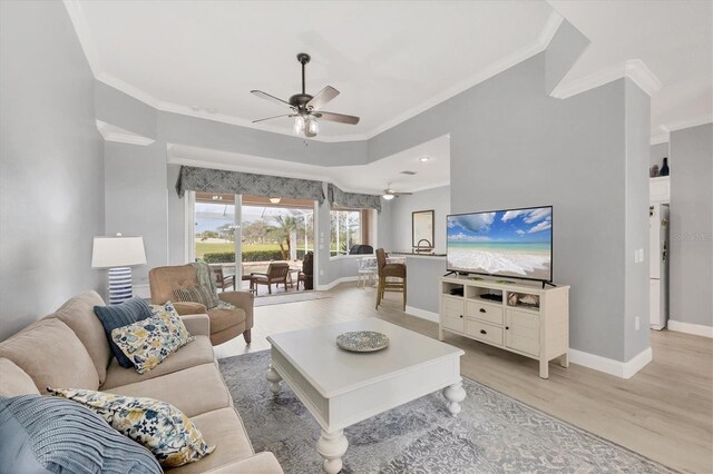 living room with light wood-type flooring, a ceiling fan, baseboards, and crown molding