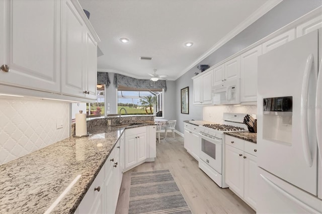 kitchen featuring ornamental molding, white cabinets, a sink, dark stone counters, and white appliances